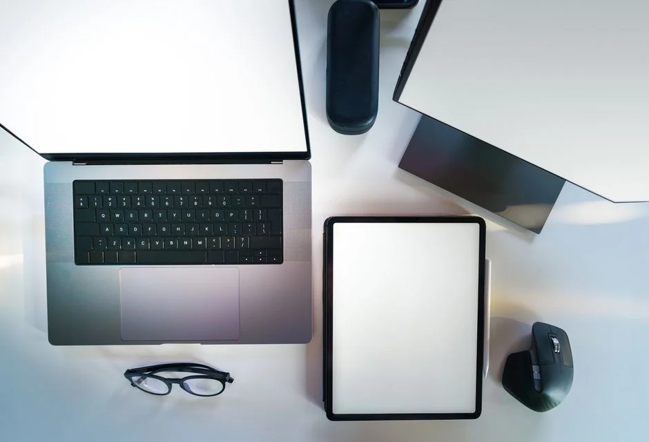 A vibrant workspace featuring a laptop, tablet, and TV with colorful lighting.